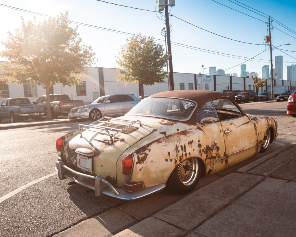 A Rat Rod styled Karmann Ghia is parked on the corner demonstrating what it's like to be the coolest thing ever.
