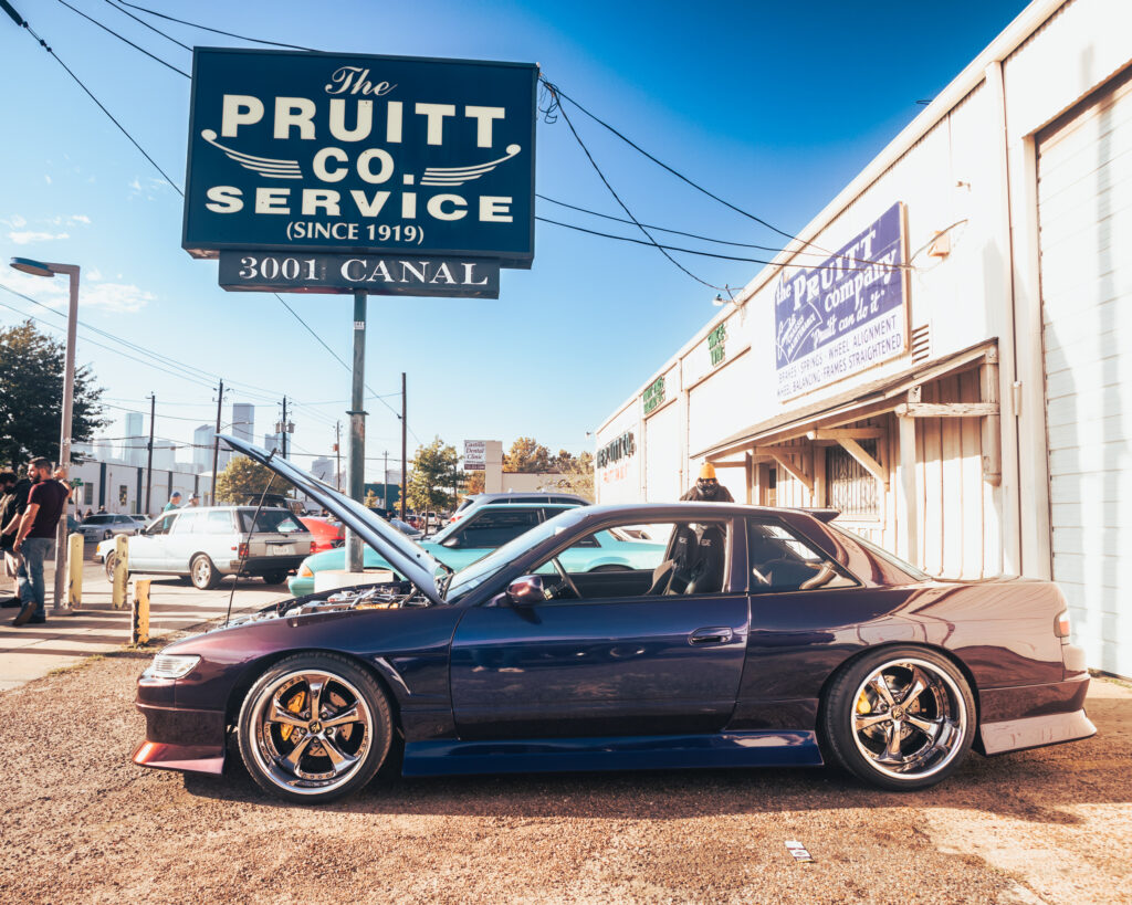 An S13 Nissan Silvia adorned in a color shift paint job throws its hood up.